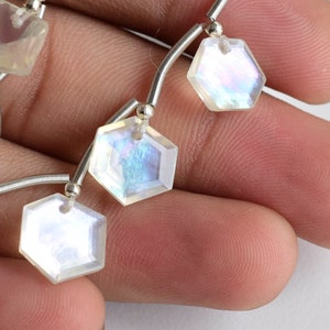 May include: A strand of iridescent white gemstone beads with a silver wire connector. The beads are faceted and have a hexagonal shape.