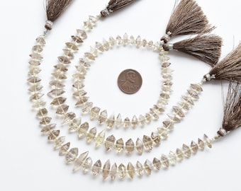 May include: Three strands of light brown faceted gemstone beads with brown tassels. The beads are arranged in a circle around a US penny for size reference.