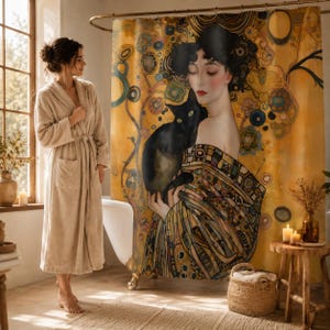 May include: A shower curtain featuring a golden-toned artistic print of a person with dark hair holding a black cat, decorated with intricate geometric and floral patterns in shades of yellow, brown, and blue, hanging in a bathroom setting.