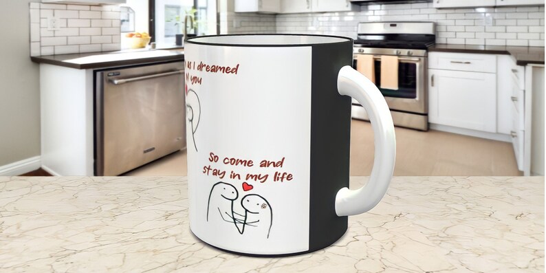 May include: White ceramic mug with a black rim and handle. The mug has a red and black illustration of two stick figures with a heart and the text "So come and stay in my life".