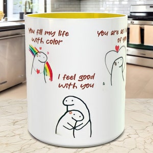 May include: White ceramic mug with a yellow rim. The mug has a cartoon illustration and the text "You fill my life with color", "I feel good with you", and "You are all of you".