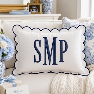 Può includere: Un cuscino rettangolare bianco con un bordo smerlato blu navy e le lettere del monogramma SMP ricamate in blu navy al centro. Il cuscino è realizzato in un tessuto liscio e presenta un distinto design decorativo del bordo.
