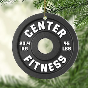 May include: Black and white Christmas ornament shaped like a weight plate with the text "CENTER FITNESS" and the weight measurements "20.4 KG" and "45 LBS".