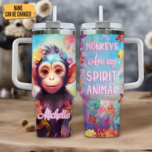 May include: A stainless steel travel mug with a white handle and straw. The mug displays a vibrant monkey design adorned with flowers, the name "Michelle", and the text "Monkeys Are my Spirit Animal."