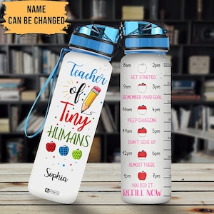 May include: A white water bottle with a blue lid and handle. The bottle has a design that says "Teacher of Tiny Humans" with a pencil and apples. The bottle also has a time-based motivational quote on the side. The name "Sophia" is written on the bottle.