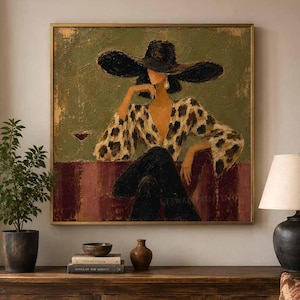 May include: A square framed oil painting depicting a person wearing a wide-brimmed black hat and a leopard print top, seated at a table with a glass of red wine. The background features muted olive green and deep burgundy tones with visible brushstrokes.