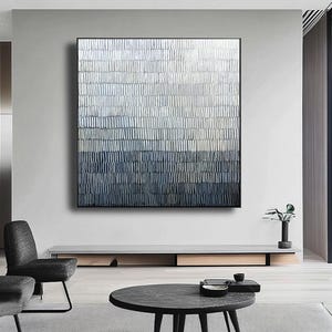 May include: Abstract wall art with a textured design in white, grey, and blue hues. The artwork is framed in black and hangs above a low, modern console. The piece adds a contemporary touch to the room.