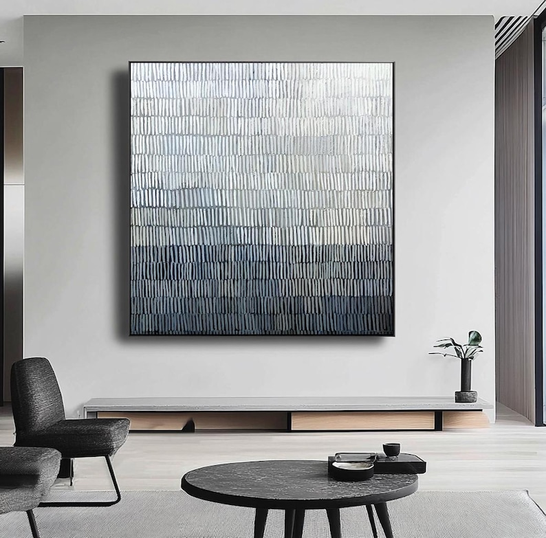 May include: Abstract wall art with a textured design in white, grey, and blue hues. The artwork is framed in black and hangs above a low, modern console. The piece adds a contemporary touch to the room.