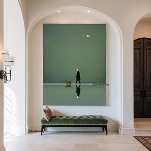 May include: A large vertical canvas print depicts a person walking a dog along a white line, reflected in the water below. The artwork features a muted green and white color palette, with a single bird in the sky. A green velvet bench sits below the artwork.