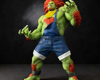 Puede incluir: Una figura humanoide musculosa de piel verde con cabello naranja salvaje y parches de pelaje naranja a juego en el pecho y los antebrazos. La figura viste un peto de mezclilla azul con puños blancos, un pañuelo amarillo y tobilleras plateadas.