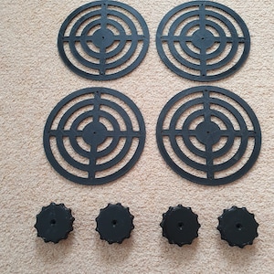 May include: Four black circular metal speaker grilles with a concentric circle design and four black plastic knobs.