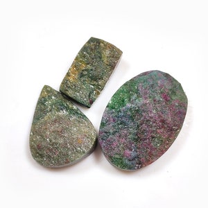 May include: Three green, pink, and gold gemstone cabochons. The cabochons are cut in a teardrop, oval, and rectangular shape.
