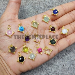 Peut inclure: Assortiment de 16 pendentifs en pierres précieuses plaqués or de forme carrée. Chaque pendentif présente une pierre précieuse différente, notamment l'améthyste, la turquoise, la rose de quartz et la pierre de lune.