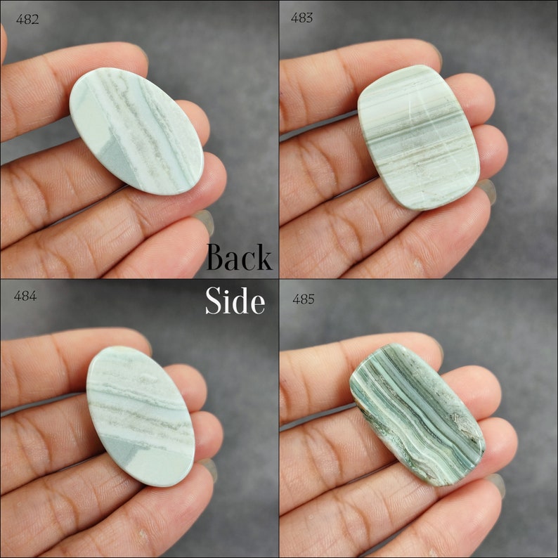 May include: Four oval and rectangular shaped green and white agate cabochons. The cabochons are smooth and polished. The cabochons are displayed on a hand.