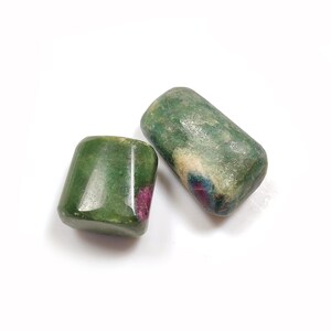 May include: Two green and pink tumbled stones. The stones are smooth and have a natural, polished look.
