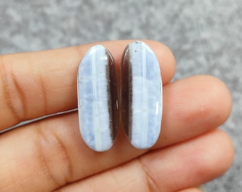 Puede incluir: Dos cabujones ovalados de ópalo azul y blanco con un centro marrón oscuro. Las piedras miden aproximadamente 2,5 cm de largo.