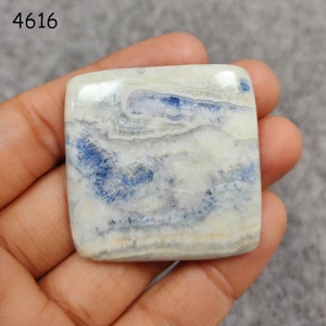 May include: A square, white and blue gemstone cabochon with a swirling pattern. The stone is approximately 2 inches wide and 2 inches long.