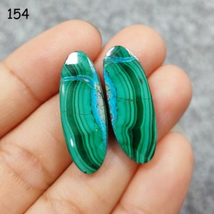 Puede incluir: Un par de cabujones ovalados de malaquita verde y azul. Las piedras tienen un patr&oacute;n de bandas y miden aproximadamente 2,5 cm de largo.