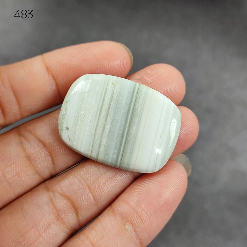 May include: A smooth, white and green banded agate cabochon with a polished finish. The cabochon is rectangular in shape and has a slightly rounded edge.