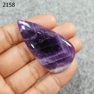 May include: A deep purple amethyst pendant with a teardrop shape and a polished finish. The pendant has a natural, striated pattern.