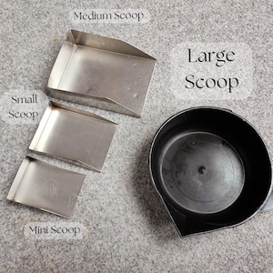 May include: A collection of scoops in various sizes. The image shows a mini, small, medium, and large scoop. The mini, small, and medium scoops are rectangular and made of metal. The large scoop is black and round.