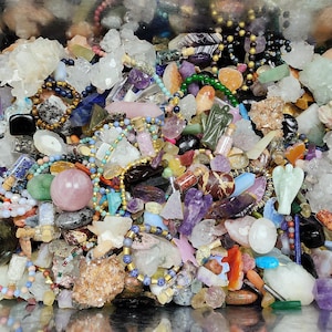 Puede incluir: Una colección de diversas piedras preciosas, cristales y cuentas de varios colores. El surtido incluye puntas de amatista, racimos de cuarzo y pulseras de cuentas. También hay pequeñas botellas y figuritas talladas.