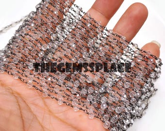 Könnte beinhalten: Eine Strähne aus klaren, facettierten Kristallperlen, die auf einer silbernen Kette aufgefädelt sind. Die Perlen haben einen Durchmesser von etwa 4 mm und die Kette ist zart und hat eine leicht oxidierte Oberfläche.