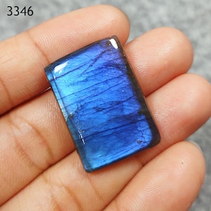 May include: A blue labradorite gemstone cabochon with a rectangular shape. The stone has a shimmery, iridescent effect.