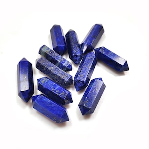 May include: A group of nine blue lapis lazuli crystal points, also known as wands, with gold flecks. The points are arranged in a cluster on a white background.