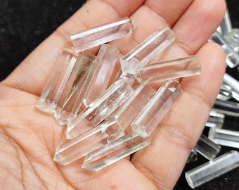 May include: A collection of clear quartz crystal points, also known as double terminated quartz, in a hand. The points are smooth and polished, with a slight green hue.