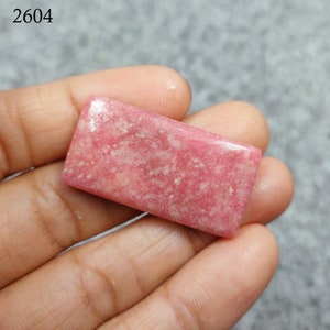 Peut inclure: Une pierre précieuse rectangulaire rose et blanche avec un motif moucheté. La pierre précieuse mesure environ 6,5 cm de long et 4 cm de large.