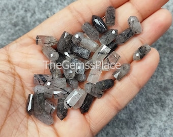 May include: A collection of black and clear faceted gemstone beads with black inclusions. The beads are approximately 1 inch long and have a pointed shape.