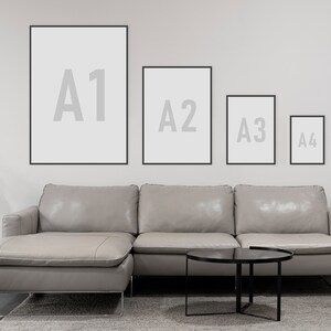 May include: Four black picture frames with white mats are hung on a white wall. The frames are labeled A1, A2, A3, and A4, from largest to smallest. A gray sectional sofa with a black coffee table sits in front of the frames.