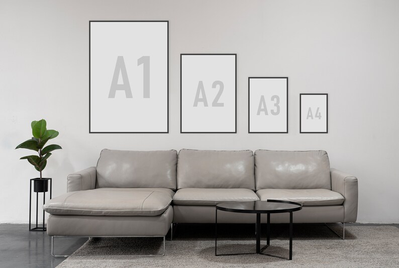 May include: Four black picture frames with white mats are hung on a white wall. The frames are labeled A1, A2, A3, and A4, from largest to smallest. A gray sectional sofa with a black coffee table sits in front of the frames.