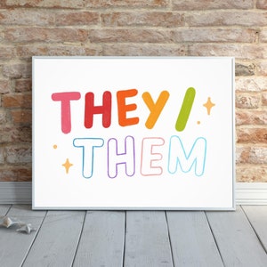 Peut inclure: Une impression encadrée blanche avec les mots "THEY/ THEM" en couleurs arc-en-ciel. Les mots sont dans un style ludique et dessiné à la main.