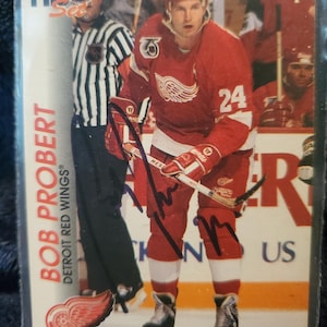 May include: A hockey trading card featuring Bob Probert of the Detroit Red Wings in a red jersey with the number 24. The card has the Pro Set logo and the Detroit Red Wings logo. The card is encased in a protective sleeve.