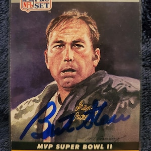 May include: An NFL Pro Set card featuring Bart Starr, quarterback for the Packers, and MVP of Super Bowl II. The card has a portrait of Starr with his signature in blue ink. The card has the NFL logo.