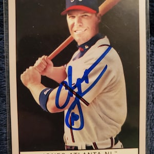 May include: A white ceramic mug with a black handle and the text "But First, Coffee" in a bold, black font. The mug is set against a neutral background, highlighting its simple design.