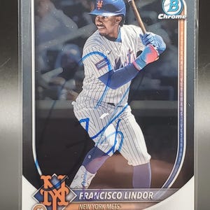Puede incluir: Tarjeta de b&eacute;isbol con Francisco Lindor de los Mets de Nueva York en posici&oacute;n de bateo. La tarjeta tiene un acabado cromado e incluye el logotipo de Bowman Chrome. El jugador lleva un uniforme a rayas azules y blancas.