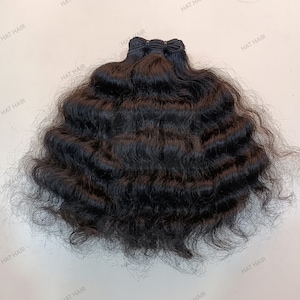 Può includere: Un pacchetto di extension per capelli castano scuro con una texture profondamente ondulata e una trama rinforzata sulla parte superiore. I capelli sono disposti a semicerchio, mostrando onde stratificate. Il testo HAT HAIR è ripetuto nell'immagine.