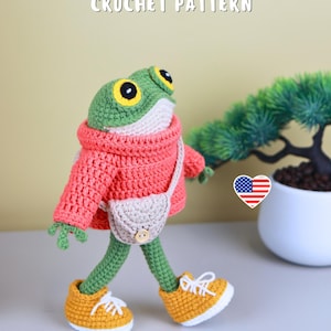 May include: A crocheted frog doll wearing a red sweater, beige purse, and yellow sneakers with white laces. The frog has green skin, large yellow eyes, and is walking. The text "CROCHET PATTERN" is at the top.