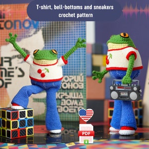 May include: Crochet pattern for a frog wearing a white t-shirt with a red cherry, blue bell-bottom pants, and white sneakers. The frog is holding a boombox. The pattern is available as a PDF download. The text on the image reads "T-shirt, bell-bottoms and sneakers crochet pattern".
