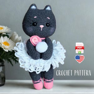 May include: Crochet pattern for a gray ballerina cat amigurumi toy. The cat is wearing a white tutu and pink ballet shoes. The pattern is available as a PDF download.