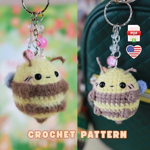 Può includere: Schema all'uncinetto per un portachiavi a forma di ape carino. L'ape è gialla e marrone con occhi neri e una piccola ala blu. Il portachiavi è attaccato a un anello argentato con perline rosa e trasparenti.