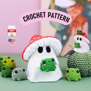 An adorable ghost wearing a red-spotted toadstool hat, cradling a tiny green frog in its hands. The ghost features black felt eyes, rosy embroidered cheeks, and a playful surprise—under its white cloak hides a hidden potato man! A whimsical handmade crochet creation full of sweet details. Perfect for Halloween decor.