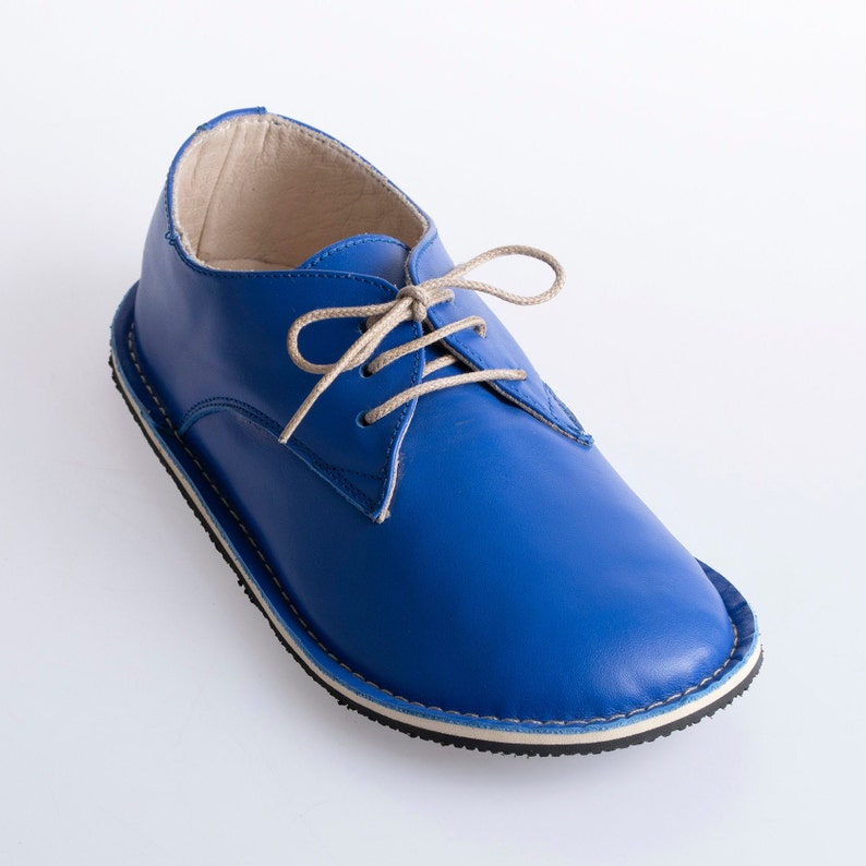 May include: A blue leather lace-up shoe with a white trim around the sole.