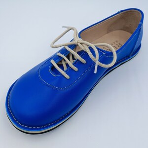 May include: Blue leather lace-up shoes with a white sole and beige laces.