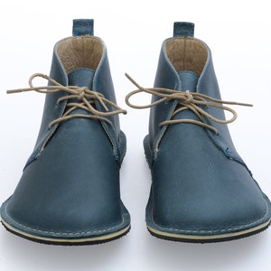 May include: A pair of blue leather ankle boots with tan laces. The boots have a rounded toe and a flat sole.