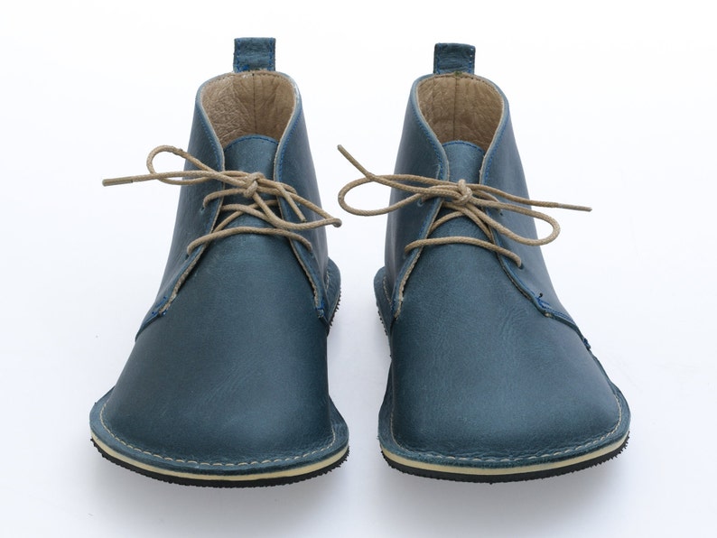 May include: A pair of blue leather ankle boots with tan laces. The boots have a rounded toe and a flat sole.
