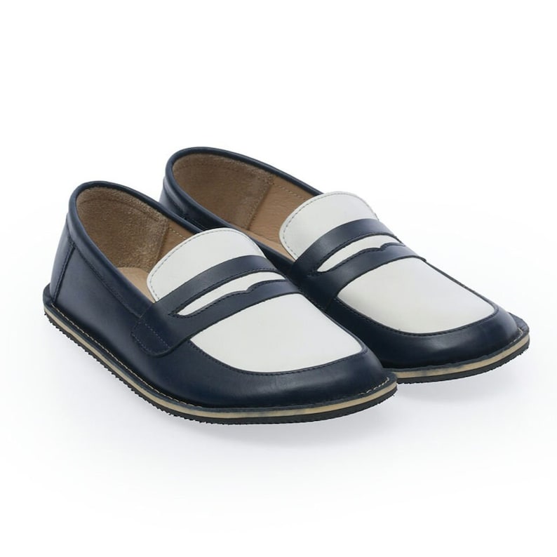 May include: A pair of blue and white leather loafers with a contrasting color design. The loafers have a rounded toe and a flat sole.